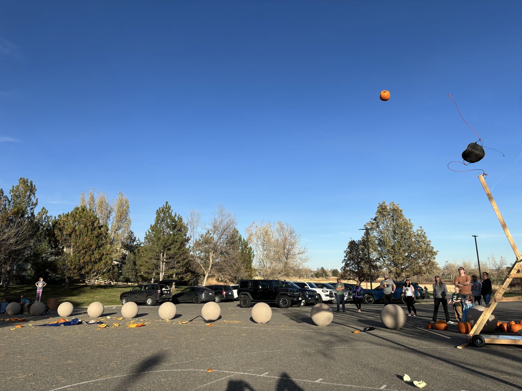 A pumpkin in flight over a parking lot as the trebuchet sling lets go
