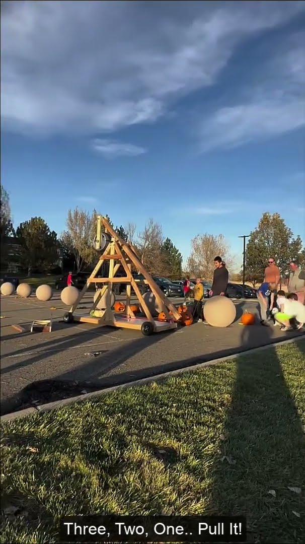 The trebuchet arm mid-swing with a pumpkin in the sling